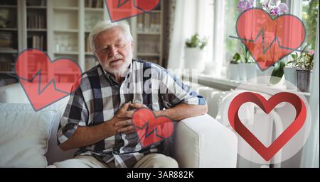 Image d'icônes de coeur au-dessus de l'homme caucasien senior dans la douleur tenant sa poitrine Banque D'Images