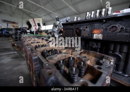 Un gros plan montre des culasses de moteur diesel démontées avec soupapes et ressorts visibles dans un atelier de réparation ou un entrepôt avec d'autres composants du moteur i. Banque D'Images