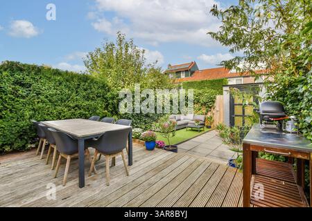 Un jardin magnifiquement aménagé avec une table à manger, une végétation luxuriante et des sièges confortables. Parfait pour les rassemblements en plein air et la détente. Banque D'Images