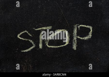 Le mot STOP écrit sur un gros plan d'un conseil scolaire noir Banque D'Images
