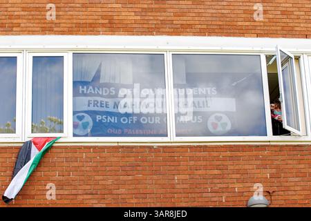 Un membre de l’Assemblée palestinienne de l’Université Queens de Belfast (QUB) lève le poing en solidarité depuis une fenêtre du bâtiment administratif du campus, qui a été occupé par un total de neuf membres du groupe étudiant activiste, pour montrer leur soutien à Mahmoud Khalil. Khalil a été enlevé de son immeuble d'habitation à New York par des agents de l'Immigration and Customs Enforcement (ICE) des États-Unis le 8 mars 2025, pour son implication en tant que négociateur principal dans le campement dans les occupations pro-palestiniennes du campus de l'Université Columbia en 2024. Date de la photo : jeudi 17 avril 2025. Banque D'Images