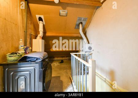 Une buanderie confortable avec une machine à laver, un sèche-linge et divers articles de rangement. L'espace est fonctionnel et pratique, conçu pour les tâches ménagères. Banque D'Images