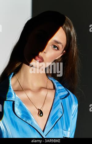 Une jeune femme gracieuse pose sur fond de lumière et d'ombre, rayonnant d'élégance. Banque D'Images