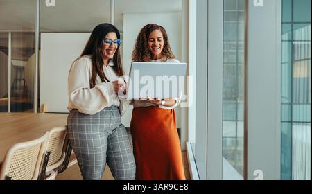 Deux femmes d'affaires travaillant en équipe dans un environnement de démarrage technologique. Ils examinent les informations sur un ordinateur portable, reflétant une collaboration et innovati Banque D'Images