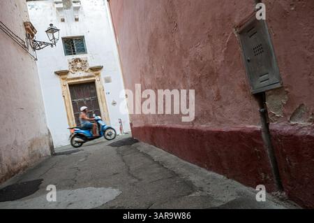 Homme sur un scooter bleu dans une ruelle à Gallipoli, Salento, Pouilles, Italie Banque D'Images