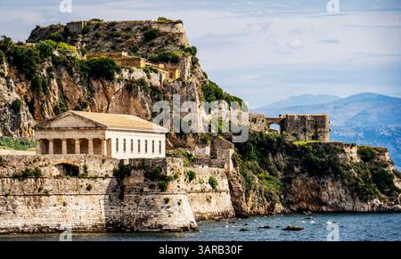 Une vue panoramique sur une forteresse historique sur une falaise rocheuse au bord de la mer, avec une architecture en pierre ancienne et une végétation luxuriante. Le ciel est partiellement nuageux, ad Banque D'Images