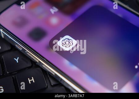 Poznan, Pologne – 14 avril 2025 : icône mobile ChatGPT affichée sur l'écran d'accueil du smartphone reposant sur le clavier de l'ordinateur portable, représentant l'utilisation moderne de l'application ai en t Banque D'Images