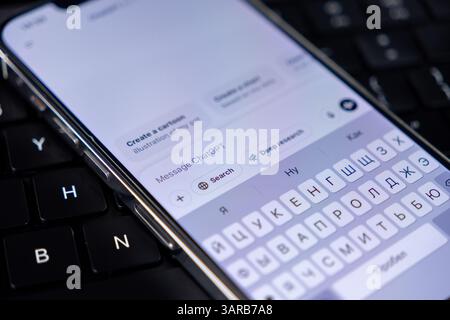 Poznan, Pologne – 14 avril 2025 : gros plan du smartphone avec application ChatGPT ouverte, clavier cyrillique actif et outils de recherche visibles, montrant le multilinguisme Banque D'Images