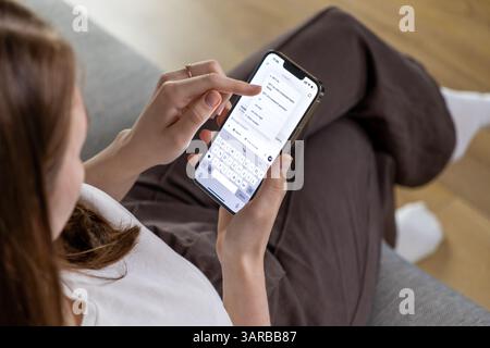 Poznan, Pologne – 14 avril 2025 : une femme tenant un smartphone et choisissant une version modèle GPT dans l’application ChatGPT, interagissant avec un int artificiel Banque D'Images