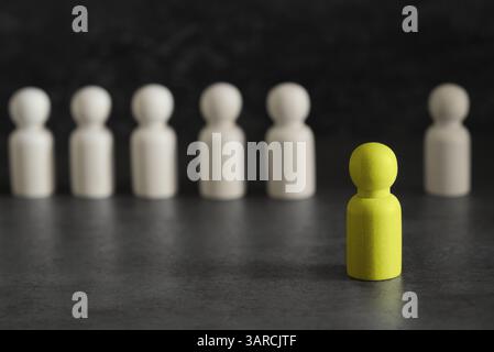 Démarquez-vous, de nouvelles idées et un leadership dans le concept d'affaires avec un chef de pion en bois jaune se démarquant et menant parmi les autres sur fond gris. Banque D'Images