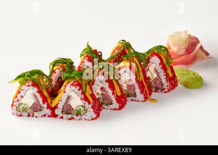 Rouleaux de sushi triangulaires recouverts de tobiko rouge avec des algues chuka et Mayo épicée sur fond blanc Banque D'Images