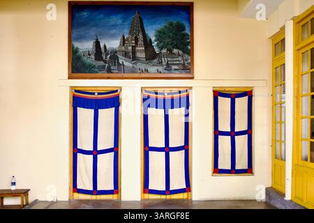 Salle intérieure au temple Dalaï Lama à Dharamshala avec des rideaux de porte tibétains et une peinture de l'arbre Bodhi à Bodh Gaya, Bihar, Inde. Banque D'Images