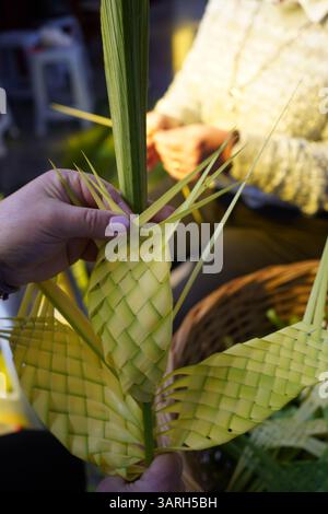 Coutume de Pâques : la main de la femme tient une création élaborée à partir de feuilles de palmier qui va être partagée avec des croix faites à la main le dimanche des Rameaux Banque D'Images