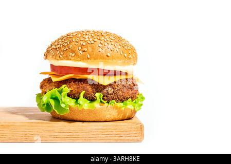 Burger de poulet, cheeseburger sur planche de bois isolé sur fond blanc, design créatif avec une lumière dure. Délicieux cheeseburger de bœuf avec américain Banque D'Images