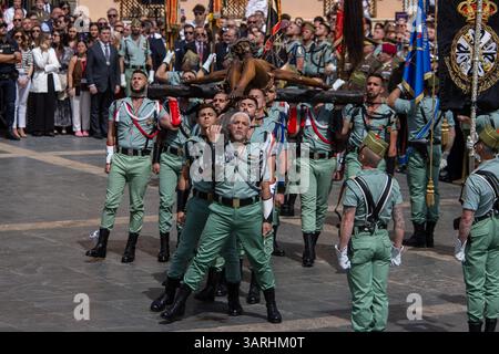 Un groupe de légionnaires porte le Christ de Mena lors du transfert du Christ de Mena le jeudi Saint, l'une des processions les plus célèbres de la semaine Sainte dans toute l'Espagne, à la fois pour ce qu'elle représente et pour la participation de la Légion en chantant 'El Novio de la Muerte', une chanson emblématique qui est devenue l'hymne officieux de la Légion espagnole. Banque D'Images