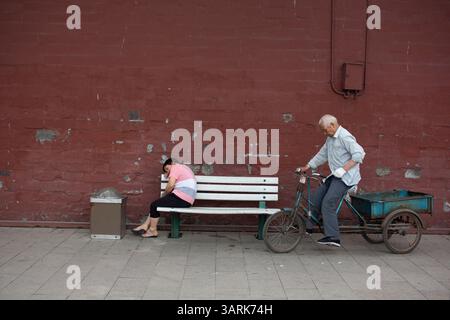 01 juil. 2013 - Pékin, Chine - Une femme était assise sur la chaise pour faire une sieste, pendant ce temps, un homme âgé voulait monter son pédicab pour partir, Pékin, Chine. (Crédit image : © Jiwei Han/ZUMAPRESS.com) Banque D'Images