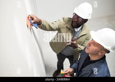 Plan à angle élevé de designers afro-américains et caucasiens regardant la palette de couleurs tout en choisissant entre orange et bleu Banque D'Images