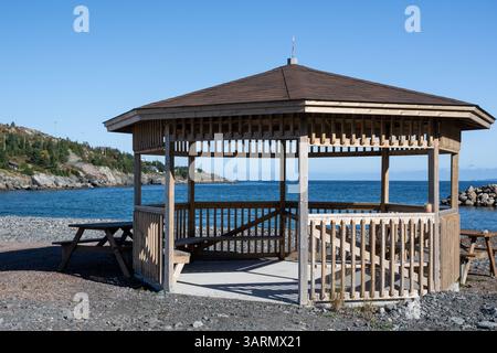Un grand belvédère en bois en forme d'octogone sur une plage surplombant l'océan. Le toit est recouvert de bardeaux bruns. Les côtés sont faits de traitement sous pression Banque D'Images