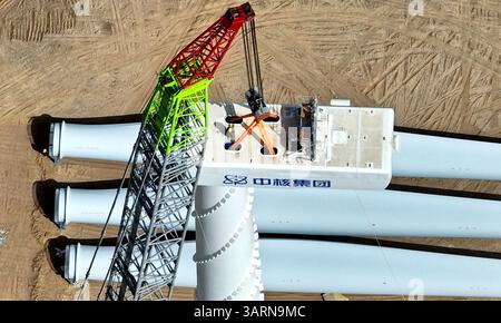 ZHANGYE, CHINE - 17 AVRIL 2025 - sur le site de construction du projet éolien de 100 000 kilowatts de Xinruisheng New Energy à Yanchi Beach, les constructeurs installent l'unité principale de l'éolienne sur une tour de 120 mètres de haut dans la ville de Zhangye, province du Gansu, Chine, le 17 avril 2025. Banque D'Images