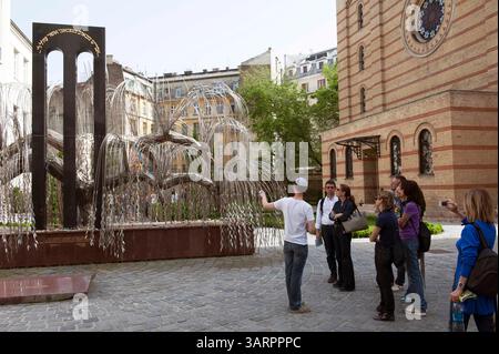 1 mai 2013 - Budapest, Hongrie - touristes avec un guide. Le Mémorial de l'Holocauste, un saule pleureur (par Imre Varga) avec les noms des Juifs hongrois tués pendant l'Holocauste inscrits sur chaque feuille, est situé dans le Parc commémoratif Raoul Wallenberg. Grande synagogue dans le quartier juif de Budapest. En 1944, la synagogue de la rue Dohany faisait partie du ghetto juif pour les Juifs de la ville et servait d'abri à beaucoup de gens. Plus de deux mille de ceux qui sont morts dans le ghetto de faim et de froid pendant l'hiver 1944-1945 sont enterrés dans la cour de la synagogue. Grande synagogue (Doha Banque D'Images