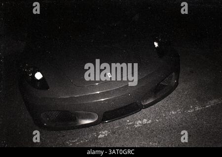 Voiture de sport élégante garée sous les étoiles révélant ses courbes élégantes et sa présence audacieuse la nuit dans une rue de la ville : Ferrari Front grille et Prancing Horse Emblem la nuit en film noir et blanc à contraste élevé, Pékin, Chine Banque D'Images