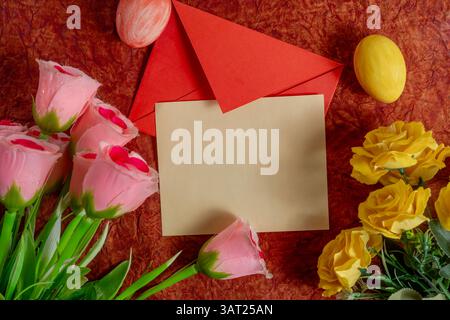 Bouquet coloré, enveloppe rouge et oeufs de Pâques disposés sur un fond texturé. Parfait pour les fêtes de fin d'année, les invitations printanières. Banque D'Images