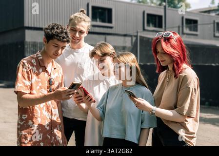 Groupe de jeunes partageant du contenu sur smartphones Banque D'Images