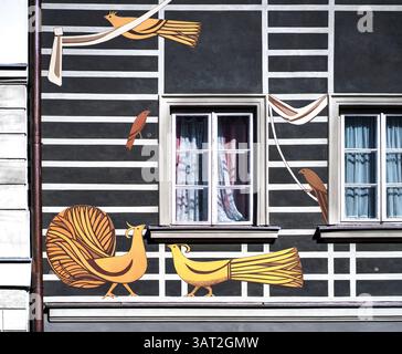 Une murale colorée sur un bâtiment présentant des oiseaux stylisés et des formes abstraites. Le dessin comprend deux oiseaux jaunes, un oiseau brun et des éléniens décoratifs Banque D'Images
