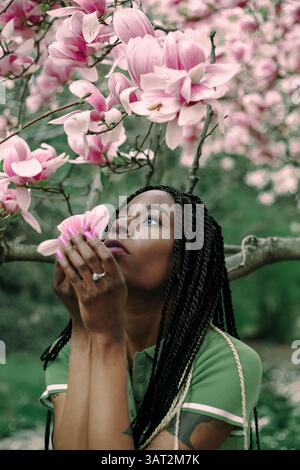 Une belle femme noire sous un magnolia fleuri Banque D'Images