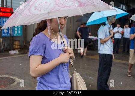 15 juillet 2013 - Pékin, Chine - en raison des heures de pointe autour de 18h et de la pluie, l'entrée de la station de métro Wudaokou devient surpeuplée, les gens attendent à l'extérieur de la station de métro, Pékin. (Crédit image : © Jiwei Han/ZUMAPRESS.com) Banque D'Images