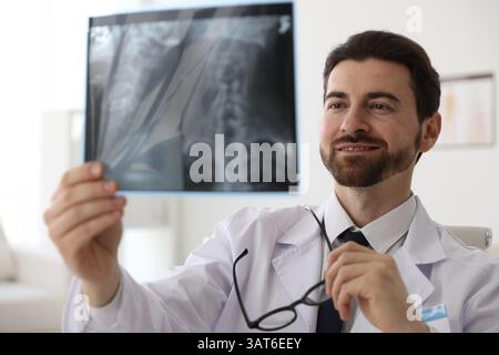 Médecin souriant examinant l'IRM du cou en clinique Banque D'Images