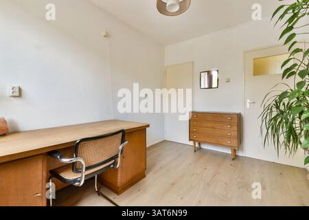 Un espace de travail élégant et minimaliste avec un bureau en bois avec une chaise, lumière naturelle et accents de plantes vertes, mettant l'accent sur un environnement calme et productif. Banque D'Images