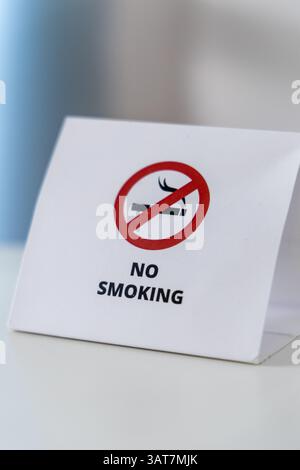 Panneau « interdiction de fumer » avec cercle rouge barré. Affiche en papier blanc sur la table avec message clair Banque D'Images