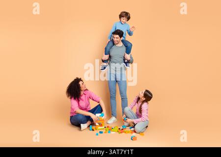 Belle famille passant du temps ensemble à jouer avec des blocs colorés et à se lier dans une atmosphère calme avec un fond beige Banque D'Images