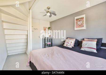 Une chambre moderne magnifiquement conçue avec des tissus d'ameublement, un décor élégant et une palette de couleurs apaisantes, créant un havre de paix parfait pour la détente. Banque D'Images