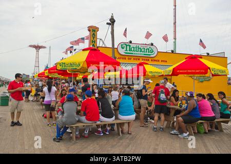10 août 2013 - Brooklyn, New York, États-Unis - à l'extérieur du célèbre restaurant de promenade de Nathan, les tables de pique-nique, avec des parapluies rouges jaunes et verts colorés, sont remplies de gens mangeant pendant la 3ème célébration annuelle de la Journée de l'histoire de Coney Island. (Crédit image : © Ann Parry/ZUMA Wire) Banque D'Images