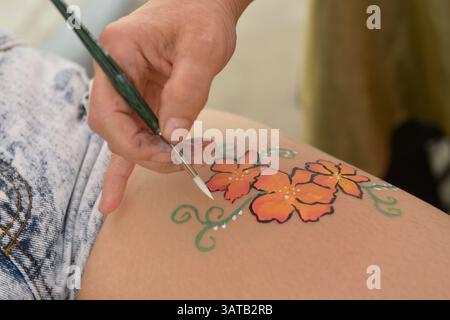 10 août 2013 - Brooklyn, New York, États-Unis - L'artiste bénévole Laura Yorburg utilise un maquillage coloré pour peindre des fleurs sur la jambe d'une jeune femme lors de la 3e célébration annuelle de la Journée de l'histoire de Coney Island. (Crédit image : © Ann Parry/ZUMA Wire) Banque D'Images