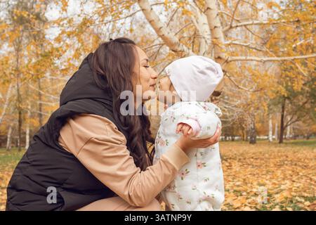 Mère et enfant partageant un moment joyeux dans Autumn Park : fusion familiale au milieu du feuillage doré Banque D'Images
