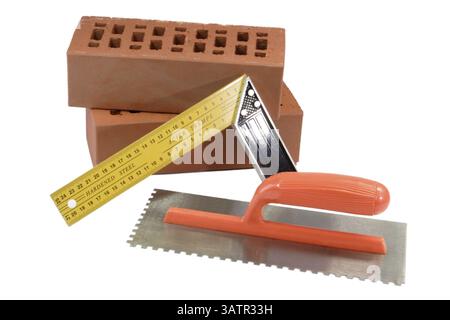 Outil de construction - isolé sur des briques de fond blanc, truelle et bâton de mètre - isolé sur fond blanc Banque D'Images