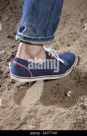 Jambes de l'homme et empreinte sur le sable Banque D'Images