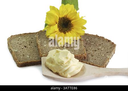 Pain avec margarine sur une cuillère en bois et tournesol Banque D'Images