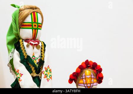 Jouets mous faits à la main habillés dans des tenues rustiques traditionnelles sur un fond blanc. Banque D'Images