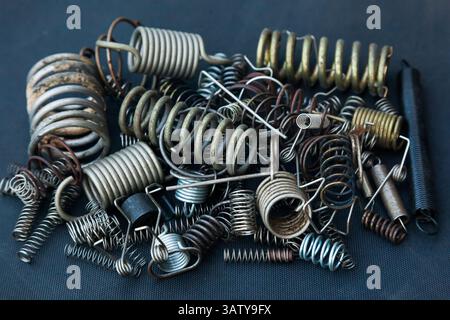 Beaucoup de petits ressorts de différentes tailles se trouvent dans un tas sur un fond noir. Banque D'Images