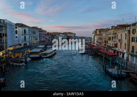 Lever de soleil sur le Grand canal depuis le pont du Rialto avec embarquement du ferry Rialto et vaporetto, San Marco (à gauche) et Dorsoduro restaurants à droite Venise. Banque D'Images