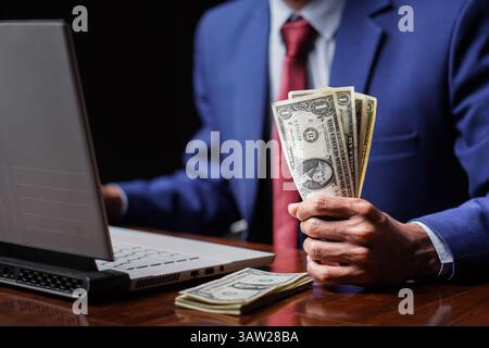 jeune homme d'affaires tenant des billets de dollar en main, concept de prêt de financement adulte aux pauvres Banque D'Images