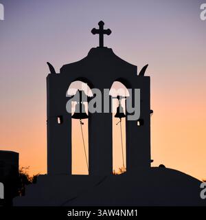 Naxos, Grèce - 25 mai 2023 : un petit beffroi grec sur une chapelle orthodoxe au crépuscule silhouetté contre le ciel du soir. Banque D'Images