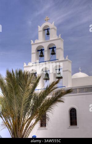 Clocher de l'église blanche de l'église d'Agia Irini avec palmier à la ville d'Oia sur l'île de Santorin. Banque D'Images