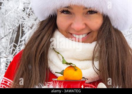Une belle fille asiatique dans un chapeau d'hiver blanc et des moufles Banque D'Images