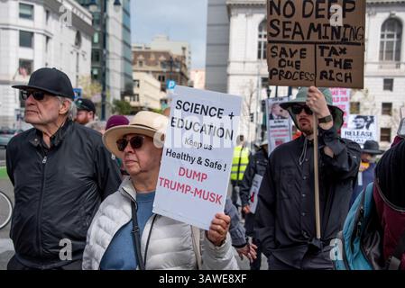 San Francisco, États-Unis. 19 avril 2025. Les manifestants écoutent des orateurs au Civic Center Plaza lors de la manifestation « Stop the Billionaire Agenda » contre l’administration Trump. Une femme tient un signe lisant, « Science + éducation nous garder en bonne santé et en sécurité ! Dump0 Trump-Musk », tandis qu'un homme derrière elle tient un panneau indiquant : « pas d'exploitation minière en haute mer. Enregistrez notre processus. Taxez les riches. » Crédit : Shelly Rivoli/Alamy Live News Banque D'Images