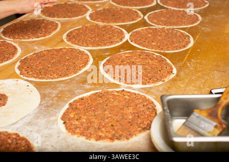 Une vue du processus de fabrication de manakish sur une surface de table en bois, dans un cadre de cuisine de restaurant. Banque D'Images